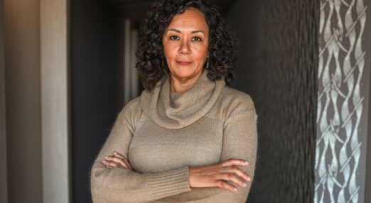 Older woman standing in entrance to her home with arms folded