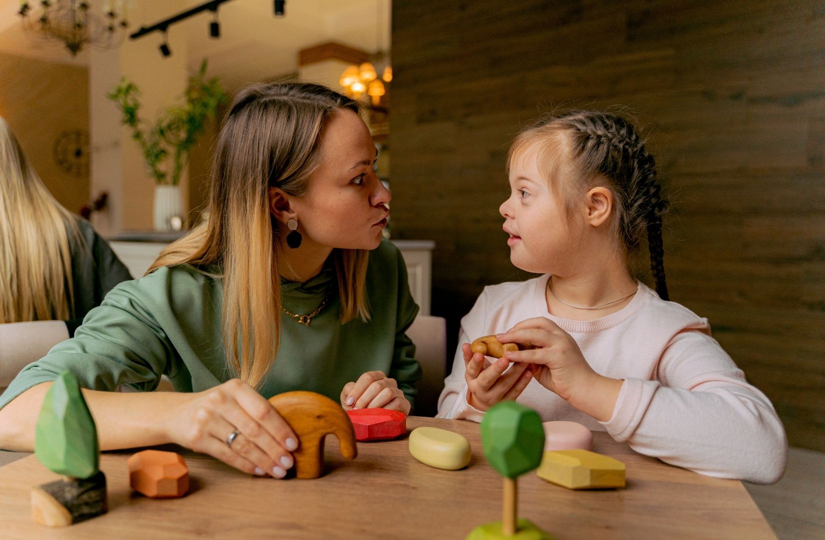 Adult woman plays with a child with Down syndrome with wooden toys