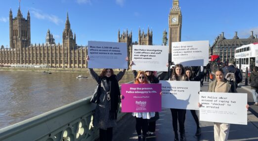 Image of staff outside parliament holding placards with headlines relating to police perpetrated abuse.