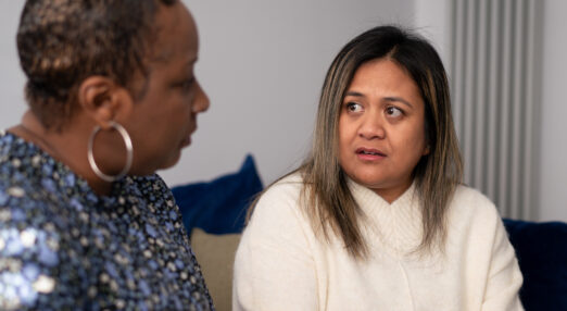 Close up of two women in a living room looking at each other with concern